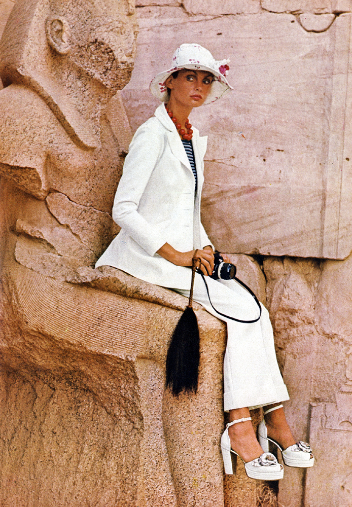 At the temple of Karnak, Jean Shrimpton wears a white Terylene gabardine suit in sharp and beautiful shape. Ossie Clark at Quorum. White hite at Feathers. White platforms shoes with silver roses, by Richard Smith for The Chelsea Cobbler. 