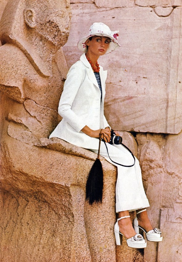 At the temple of Karnak, Jean Shrimpton wears a white Terylene gabardine suit in sharp and beautiful shape. Ossie Clark at Quorum. White hite at Feathers. White platforms shoes with silver roses, by Richard Smith for The Chelsea Cobbler. 