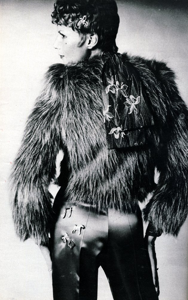 Long haired brown Acrylic jacket with plain straight from by Gordon King. Scarlet satin trousers from Wallis Shops. Black and white orchid print blouse by John Craig. Diamante comb by Adrien Mann. Musical note brooch and doggy brooch by Corocraft. Other jewellery by Bus Stop.