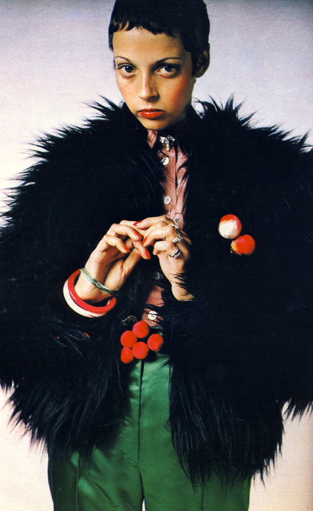 Chunky fake fox Borg jacket with orange satin lining and shiny satin trousers both from Wallis Shops. Feather embossed crepe de chine shirt by Ronnie Stirling at Stirling Cooper. Dog brooch by Corocraft. Rings by Adrien Mann. Flocked peaches and cherries both by Adrien Mann.